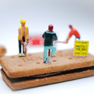 Close-up of a document with the words ‘Labor Law Compliance’ surrounded by legal textbooks, a gavel, and a laptop showing compliance dashboard graphics