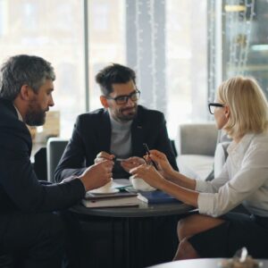 A professional businessperson confidently negotiating at a table with a client, with a laptop and negotiation materials on the table. The image illustrates effective communication and closing techniques in a business negotiation